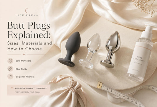 Luxury flat-lay of beginner-friendly butt plugs with flared bases, anal lubricant, toy cleaner, satin pouch and sizing guide.