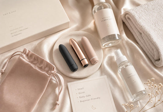 Luxury flat-lay of beginner-friendly bullet vibrators with water-based lubricant, toy cleaner, satin pouch, folded towel and note card.