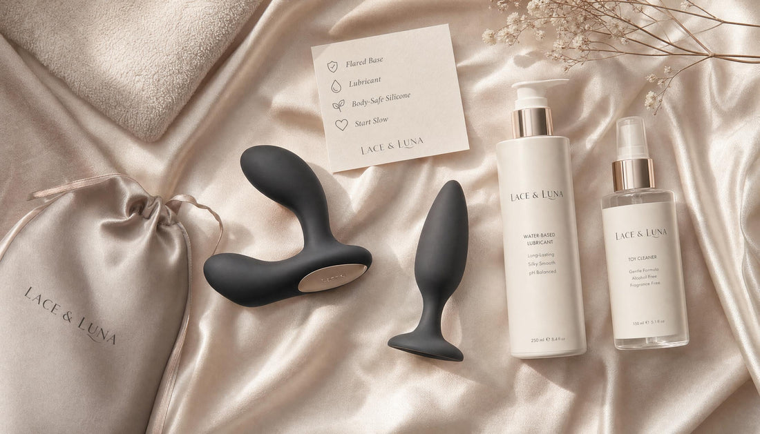 Luxury flat-lay of prostate massager, thick anal lubricant, toy cleaner, satin pouch, towel and safety note card.